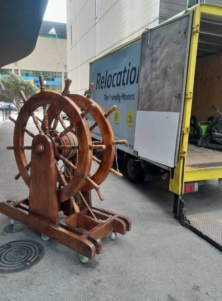 A ship's wheel on a trolley beside the open RelocatioNZ truck
