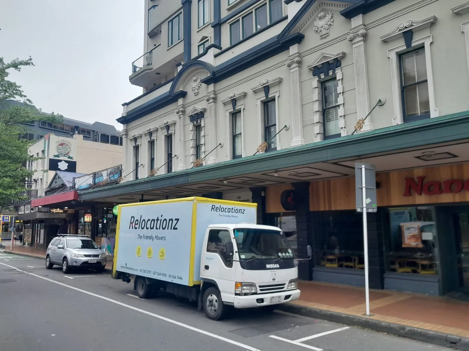 RelocatioNZ truck parked outside a row of Wellington shops