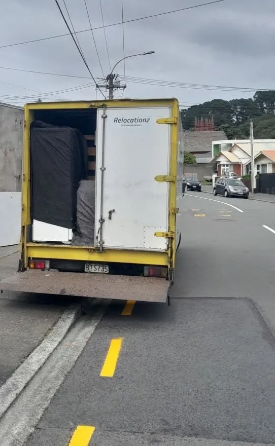 RelocatioNZ truck loaded with furniture, tail-lift down on a Wellington street